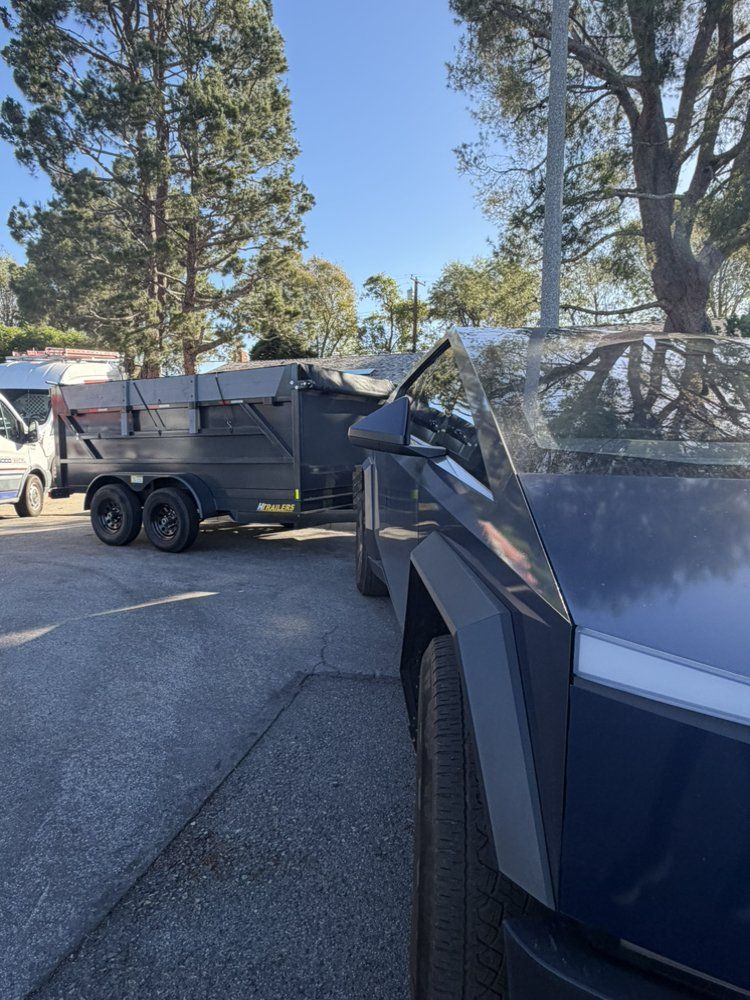 Black dump trailer hitched to an electric pickup truck