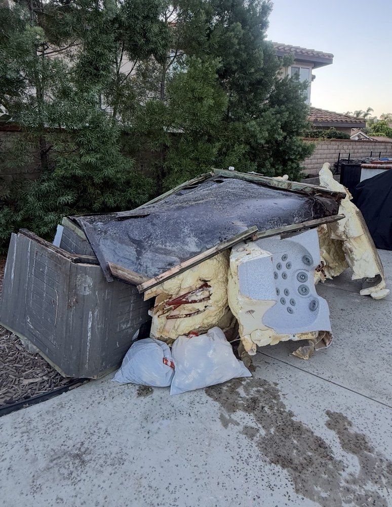 Old hot tub broken apart on a driveway, ready for removal